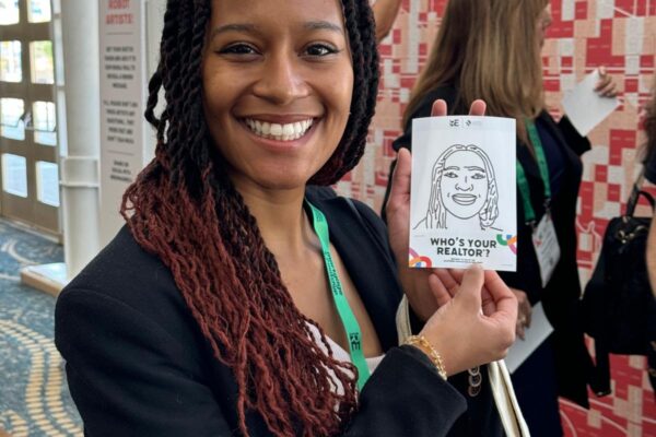 Lady holding a drawing of her face from the Sketchbot at REimagine! 2024