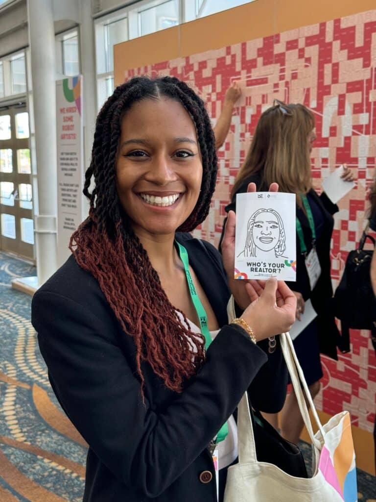 Lady holding a drawing of her face from the Sketchbot at REimagine! 2024