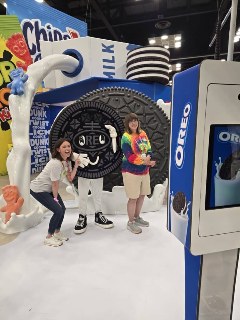 Two ladies taking a picture with the big oreo Mascot at Sweets and Snacks Expo 2025