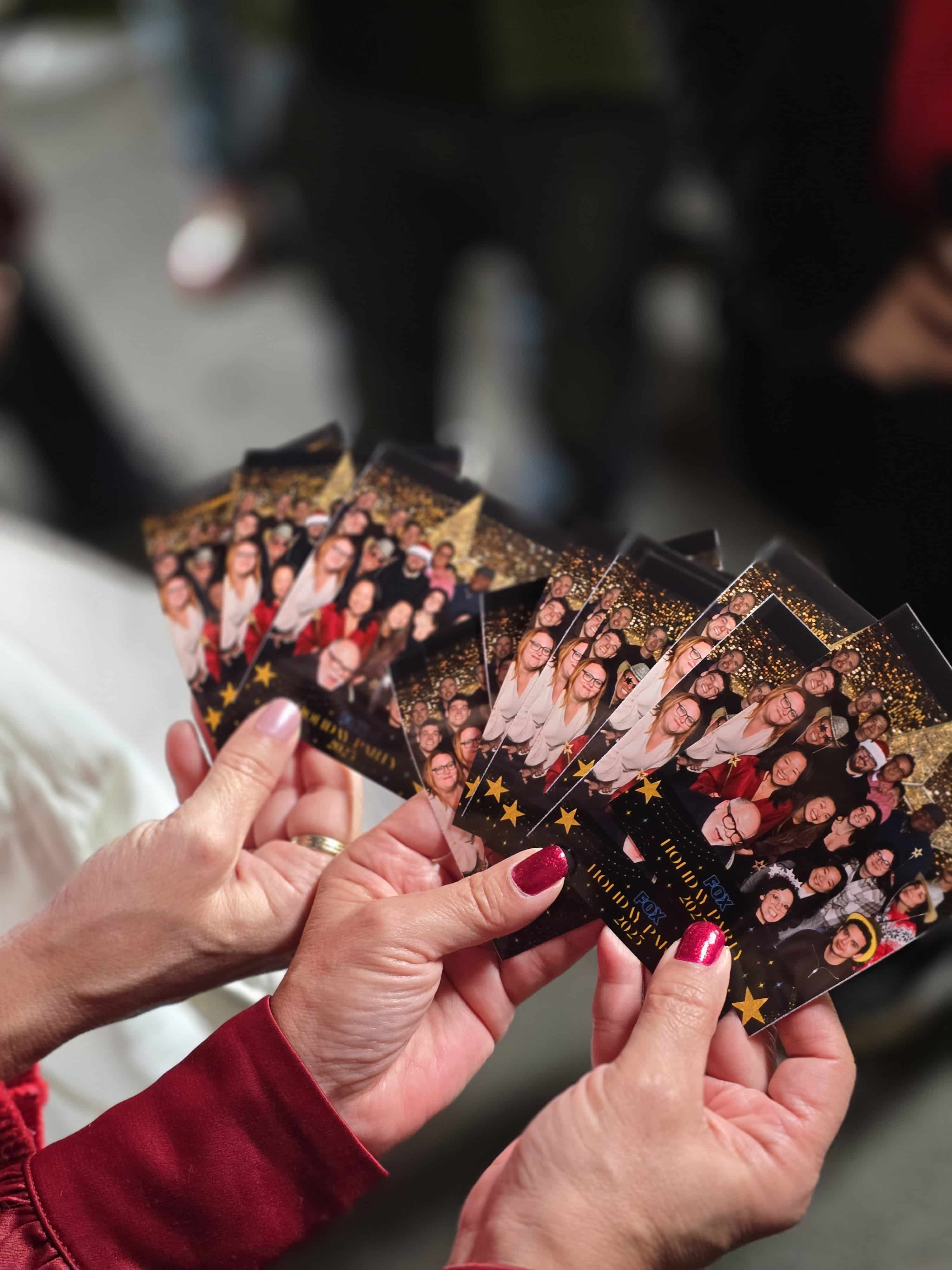 Ladies holding multiple photo prints on their hands at the Fox Holiday Party 2025