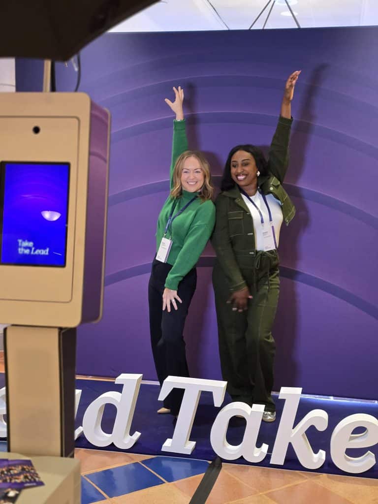 Two ladies posing in front of the ITA Group 2026 photo booth