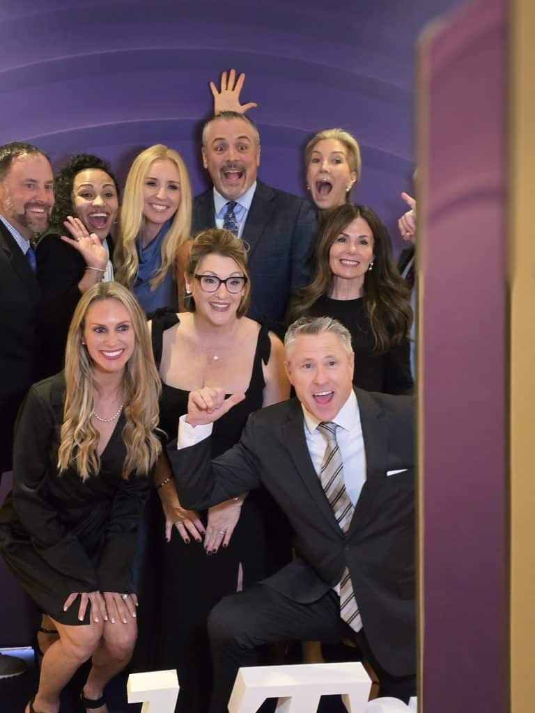 A large group of people dressed for the ITA group Gala posing in front of the Photo booth