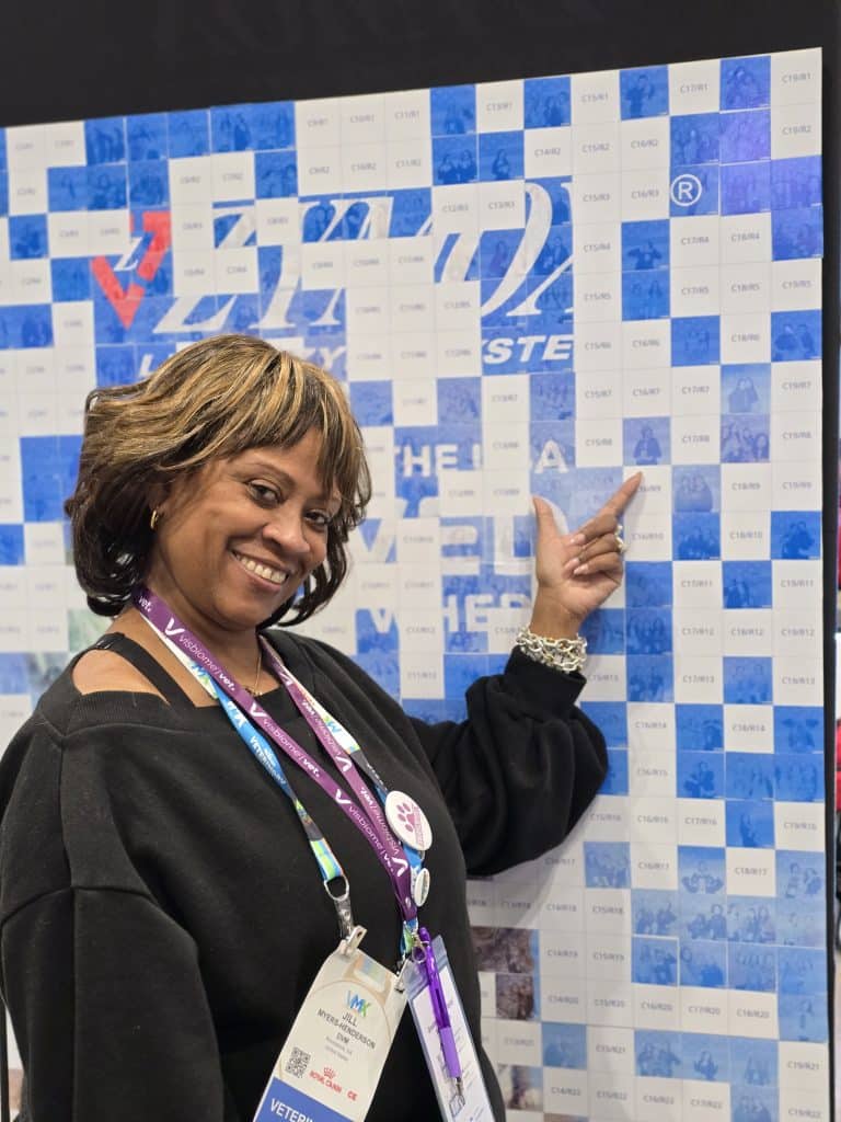 VMX 2026 Photo 4 A lady showing her picture on the photo mosaic wall