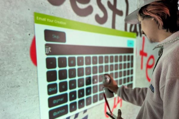 A guy typing his email on the graffiti wall