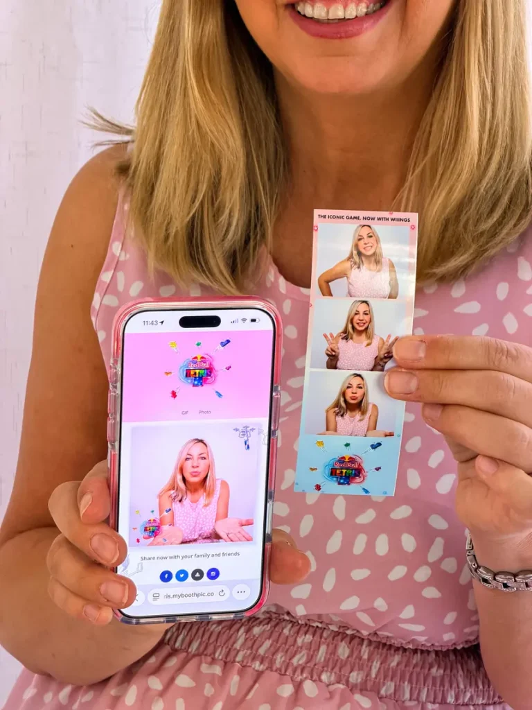 enclosed-booth2026-28 A lady with a pink dress holding her print strip photos and her phone with her digital pictures