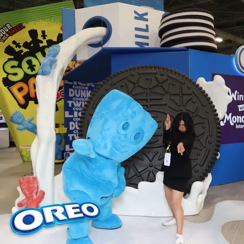A lady and a Sour Patch Kid Mascot posing at the GIF booth at the Sweets and snacks expo 2026
